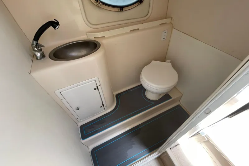 Slide: The Image of Compact bathroom in a 2000 Rinker 280 Express Cruiser, featuring a sink and toilet. - 44