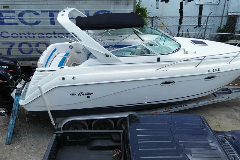 Slide: The Image of 2000 Rinker 280 Express Cruiser on trailer, white exterior, parked near a building. - 8