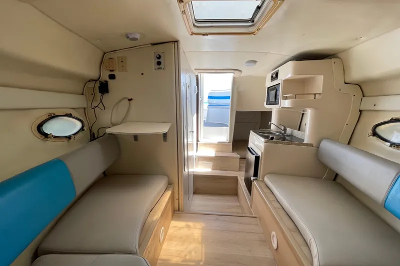 Slide: The Image of Interior of 2000 Rinker 280 Express Cruiser with seating, kitchenette, and natural light. - 47