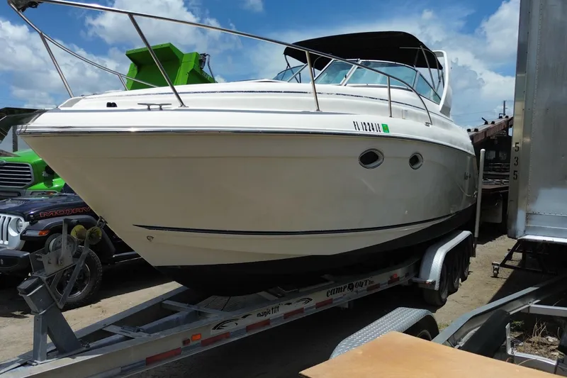 Slide: The Image of 2000 Rinker 280 Express Cruiser on trailer, parked outdoors under a clear sky. - 16