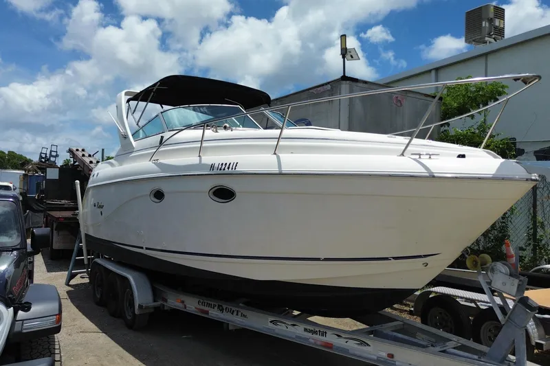 Slide: The Image of 2000 Rinker 280 Express Cruiser on trailer, parked outdoors under a blue sky. - 15