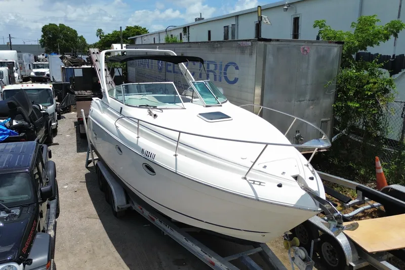 Slide: The Image of 2000 Rinker 280 Express Cruiser on trailer in industrial area, sunny day. - 10