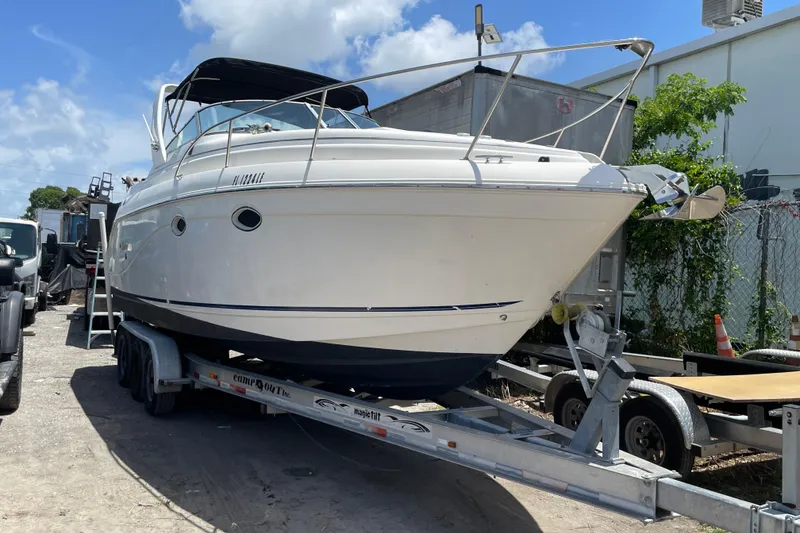 Slide: The Image of 2000 Rinker 280 Express Cruiser on trailer, parked outdoors under blue sky. - 22