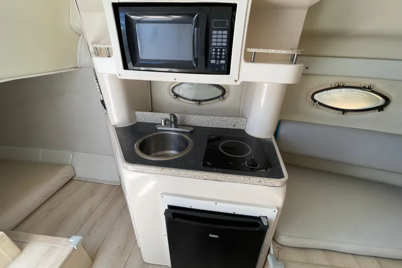 Slide: The Image of Compact galley in 2000 Rinker 280 Express Cruiser with microwave, sink, and cooktop. - 49