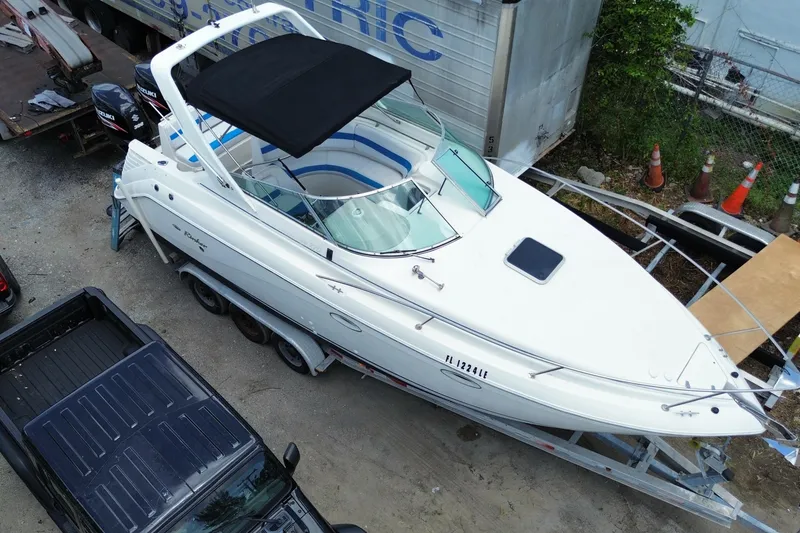 Slide: The Image of 2000 Rinker 280 Express Cruiser on trailer, aerial view, parked near vehicles and equipment. - 2