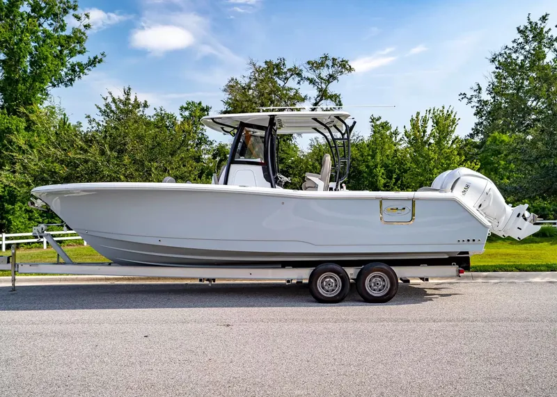 Slide: The Image of A 2027 Sea Hunt Ultra 285 SE on a trailer, surrounded by trees and blue sky. - 2