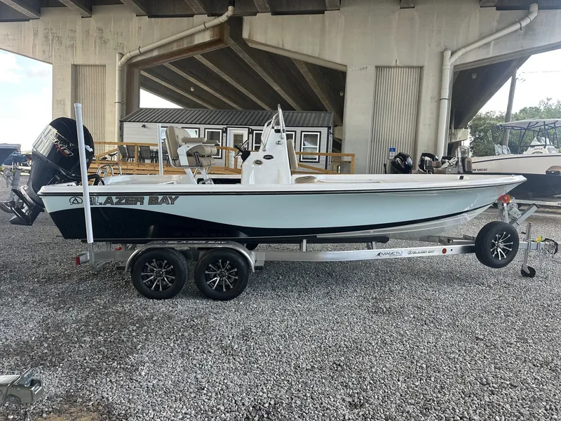 The Image of A Blazer 2200 PURE BAY boat on a trailer under a bridge. - 1