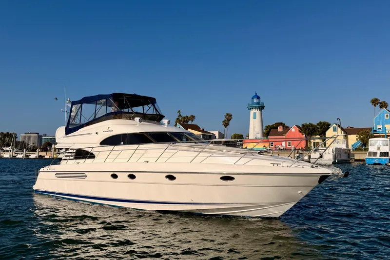 Slide: The Image of 2001 Fairline 55 yacht cruising near colorful waterfront buildings and lighthouse. - 1