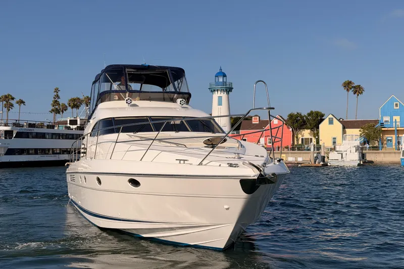 Slide: The Image of Luxury Fairline 55 yacht from 2001 cruising near colorful waterfront buildings and lighthouse. - 138