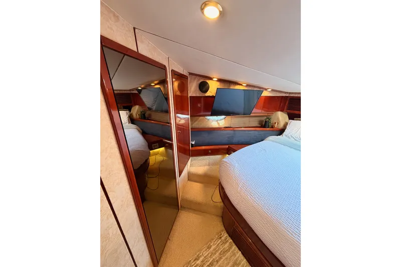 Slide: The Image of Luxurious cabin interior of a 2001 Fairline 55 yacht, featuring elegant wood finishes and cozy bedding. - 115
