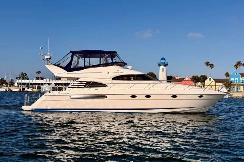 The Image of 2001 Fairline 55 yacht cruising near colorful waterfront buildings and lighthouse. - 0