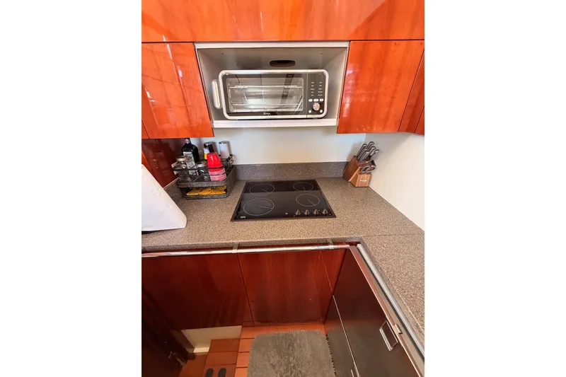 Slide: The Image of Kitchen area of 2001 Fairline 55 yacht with stove, microwave, and wooden cabinetry. - 31