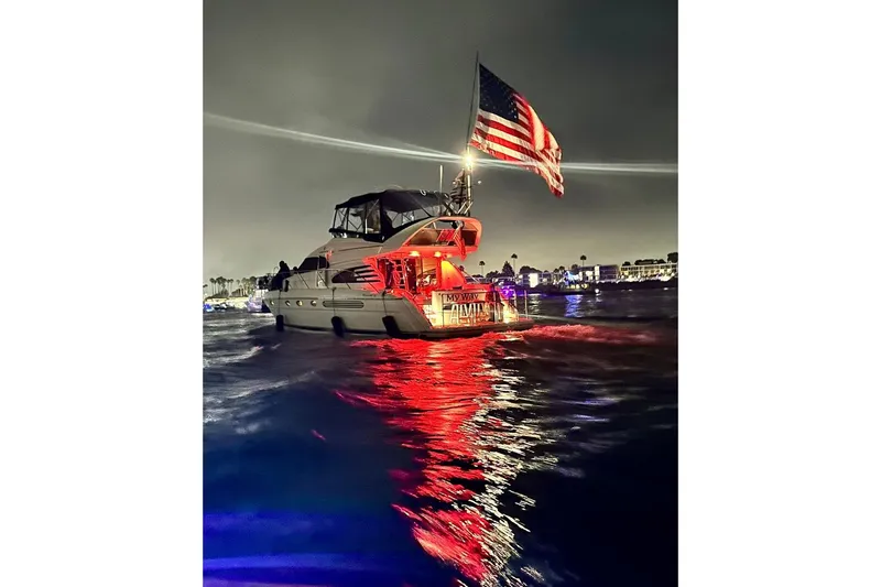 Slide: The Image of 2001 Fairline 55 yacht with American flag, illuminated at night on water. - 141