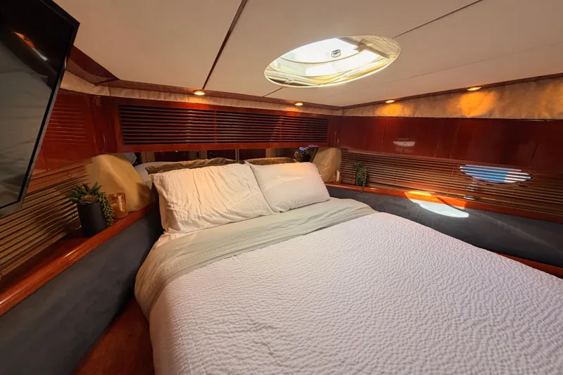 Slide: The Image of Luxurious cabin interior of a 2001 Fairline 55 yacht with cozy bedding and elegant wood finishes. - 117