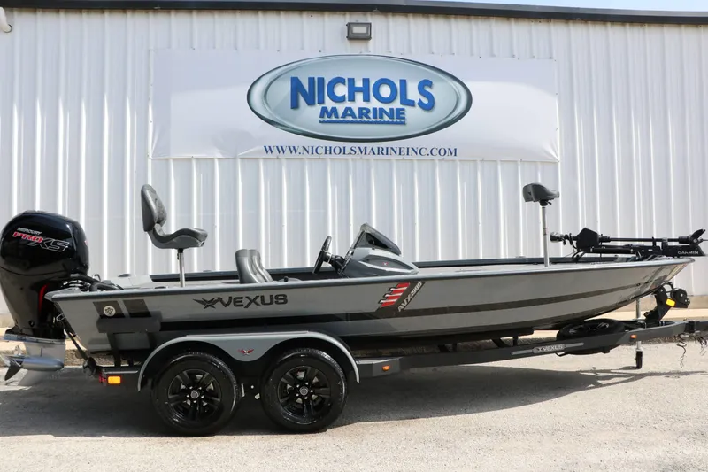 Slide: The Image of A Vexus AVX 1980 boat on a trailer in front of a building with a Nichols Marine sign. - 2