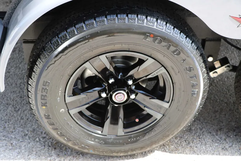 Slide: The Image of Close-up of a black tire with a shiny rim on a Vexus AVX 1980 boat trailer. - 19