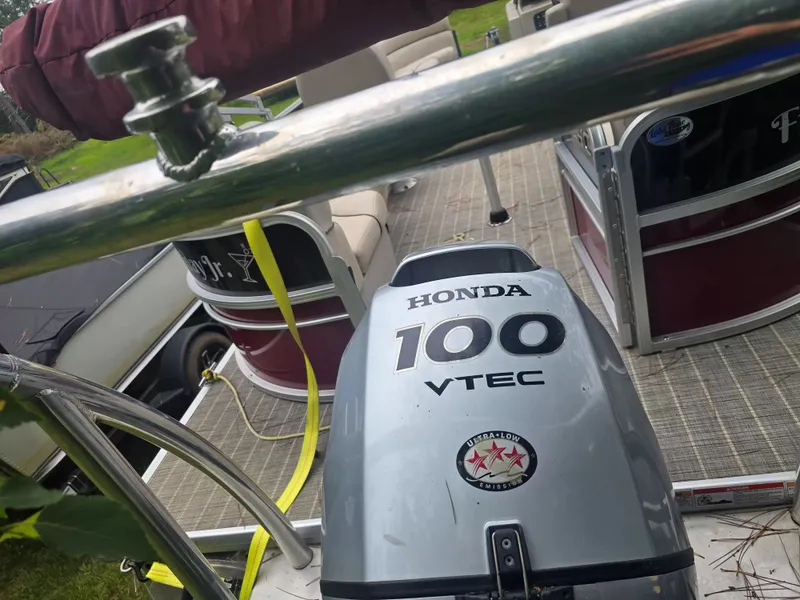 Slide: The Image of A Honda 100 VTEC outboard motor on a pontoon boat with seating and railings. - 11