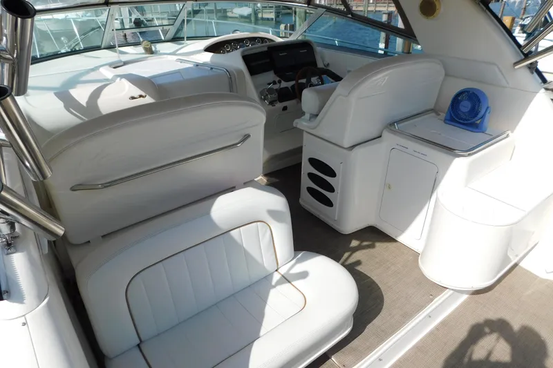 Slide: The Image of 1997 Sea Ray 330 Express Cruiser interior with white seating and helm, docked at marina. - 11