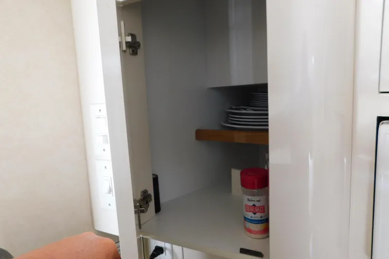 Slide: The Image of Open cabinet on 1997 Sea Ray 330 Express Cruiser, showing plates and salt container. - 70