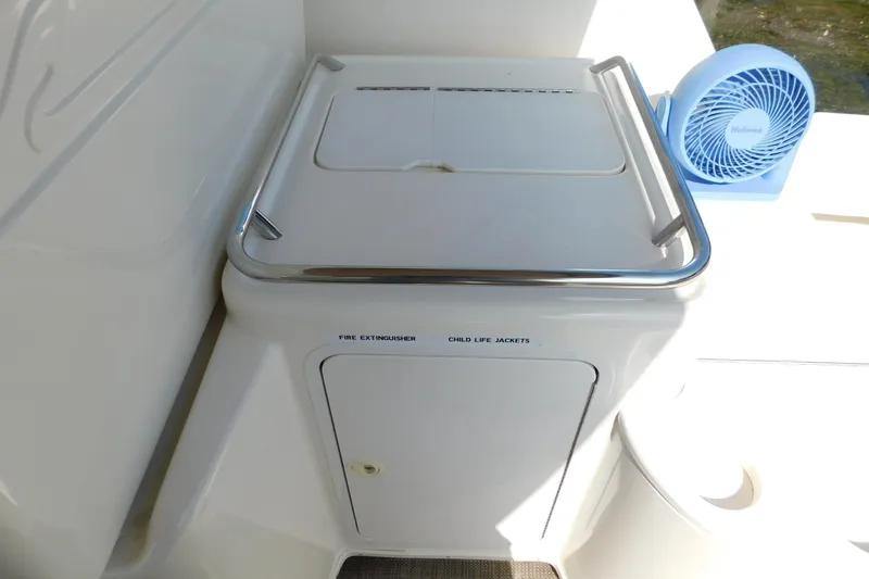 Slide: The Image of 1997 Sea Ray 330 Express Cruiser storage compartment with safety equipment and a small fan. - 20
