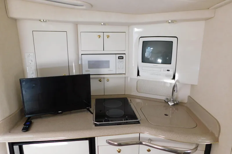 Slide: The Image of 1997 Sea Ray 330 Express Cruiser kitchen with TV, microwave, stove, and sink. - 66