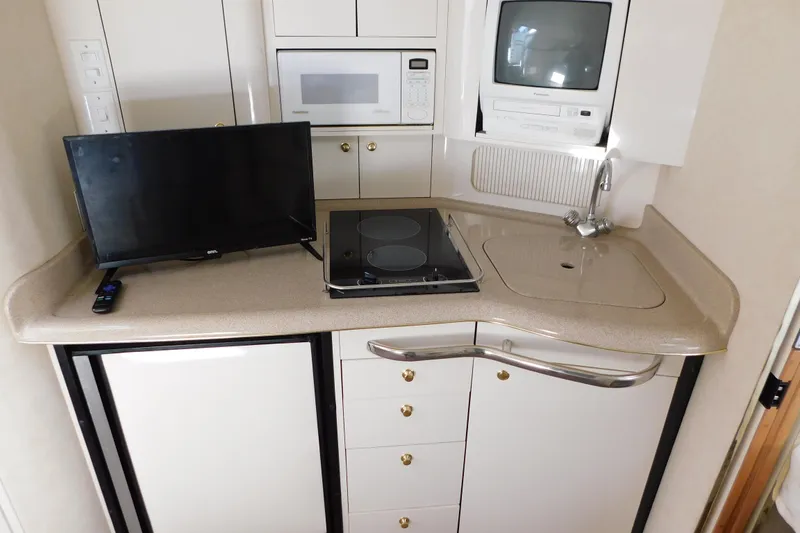 Slide: The Image of 1997 Sea Ray 330 Express Cruiser galley with TV, microwave, stove, and sink. - 65