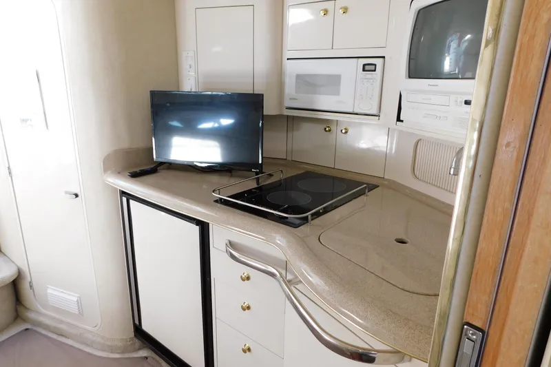 Slide: The Image of 1997 Sea Ray 330 Express Cruiser interior kitchen with TV, microwave, and stovetop. - 76