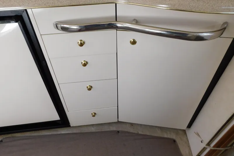 Slide: The Image of 1997 Sea Ray 330 Express Cruiser interior cabinetry with sleek white finish and gold knobs. - 74