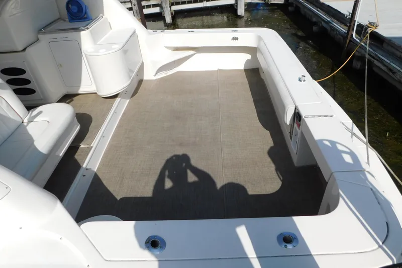 Slide: The Image of 1997 Sea Ray 330 Express Cruiser deck with seating and storage, docked at marina. - 7