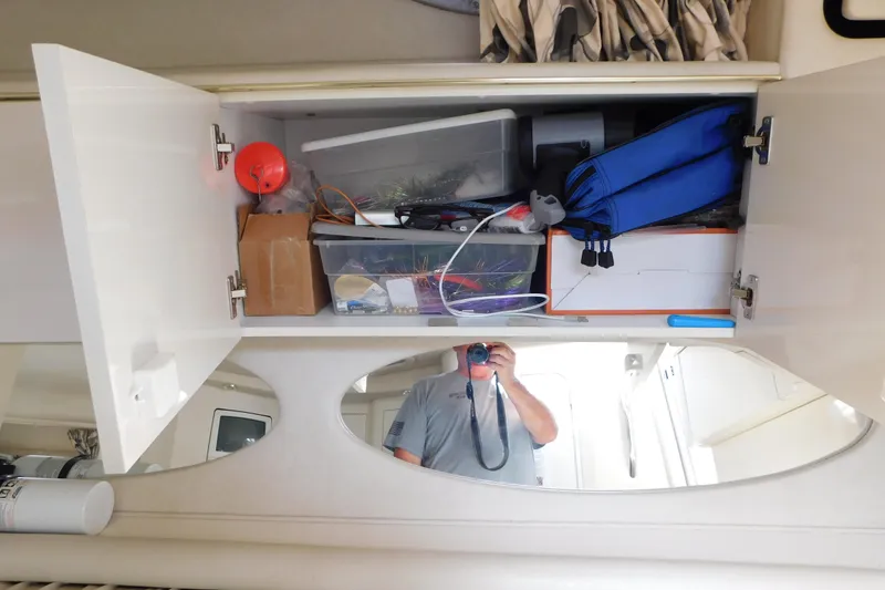 Slide: The Image of Open cabinet with assorted items inside a 1997 Sea Ray 330 Express Cruiser. - 56