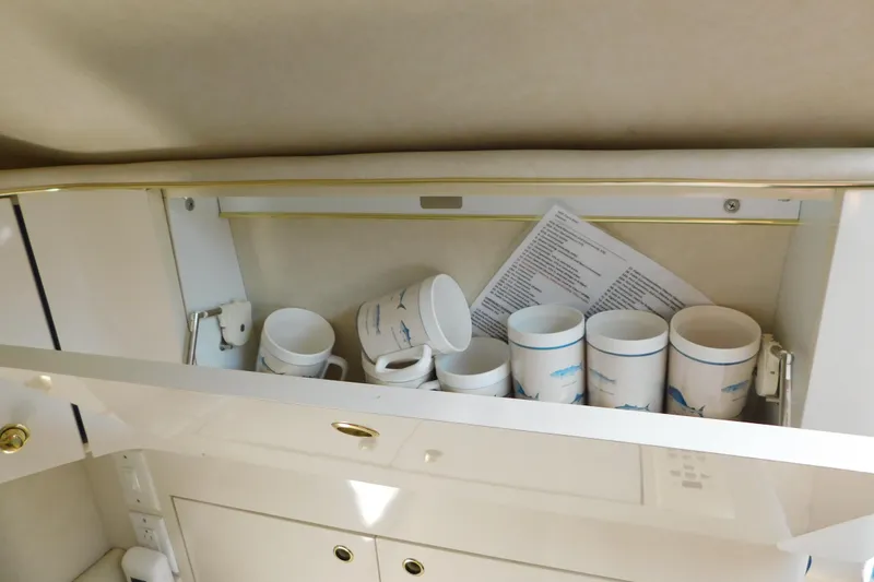 Slide: The Image of Cabinet with cups and papers inside a 1997 Sea Ray 330 Express Cruiser. - 51