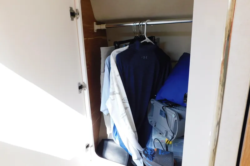 Slide: The Image of Closet inside 1997 Sea Ray 330 Express Cruiser with clothes and storage items. - 60