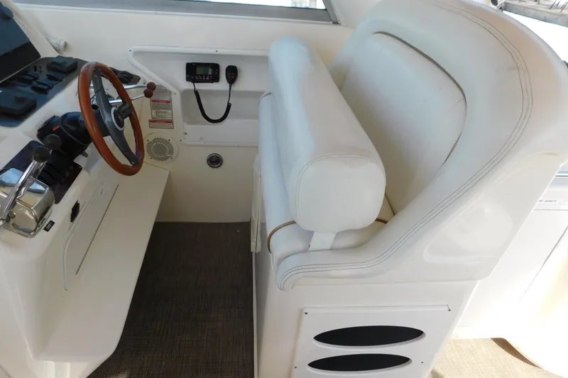 Slide: The Image of 1997 Sea Ray 330 Express Cruiser helm with white seating and wooden steering wheel. - 25