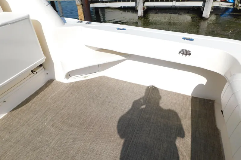 Slide: The Image of 1997 Sea Ray 330 Express Cruiser deck area with beige flooring and seating. - 16