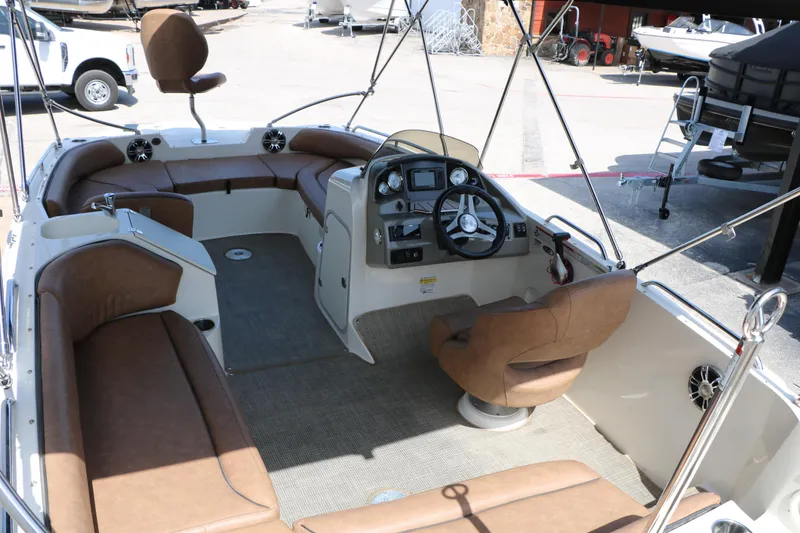 Slide: The Image of 2022 Stingray 192 SC boat interior with brown seating and modern dashboard. - 20
