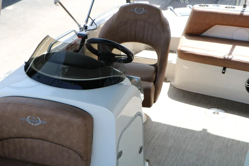 Slide: The Image of 2022 Stingray 192 SC boat interior with brown seating and steering wheel. - 30