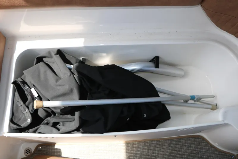 Slide: The Image of Storage compartment in a 2022 Stingray 192 SC boat with folded fabric and metal poles. - 37