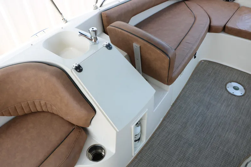 Slide: The Image of 2022 Stingray 192 SC boat interior with brown seating and built-in sink. - 26