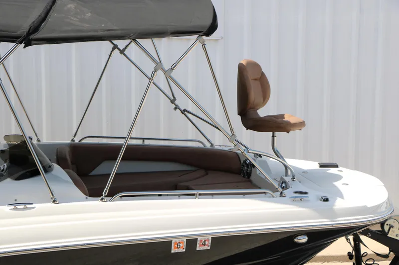 Slide: The Image of 2022 Stingray 192 SC boat with brown seating and canopy, docked near a white wall. - 13