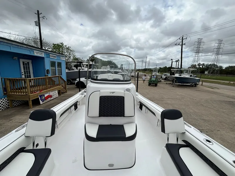 Slide: The Image of The image shows a Tidewater 2500 Carolina Bay boat in a parking area. It has white and black seating. - 3