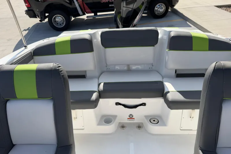 Slide: The Image of 2024 Tahoe T21 boat interior with gray and green seating, parked on concrete. - 21