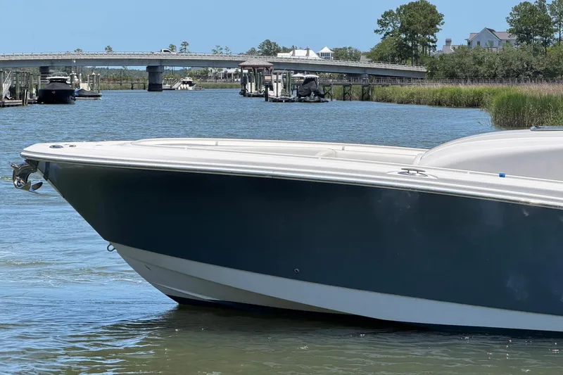 Slide: The Image of 2016 Edgewater 368CC boat on calm water near a bridge and greenery. - 5