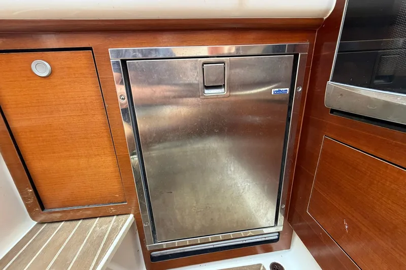 Slide: The Image of Stainless steel fridge on 2016 Edgewater 368CC boat, surrounded by wooden cabinetry. - 49