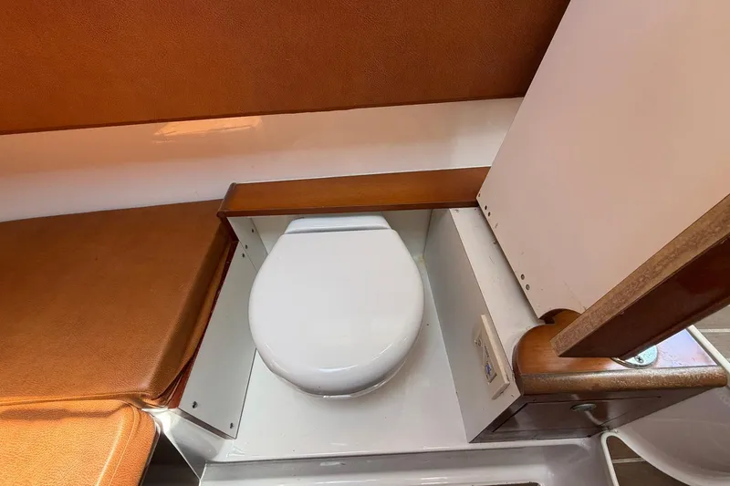 Slide: The Image of 2016 Edgewater 368CC boat interior with compact marine toilet and wooden accents. - 51