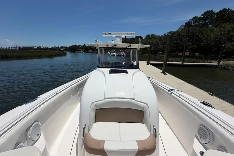Slide: The Image of 2016 Edgewater 368CC boat docked by a serene waterfront under a clear blue sky. - 31
