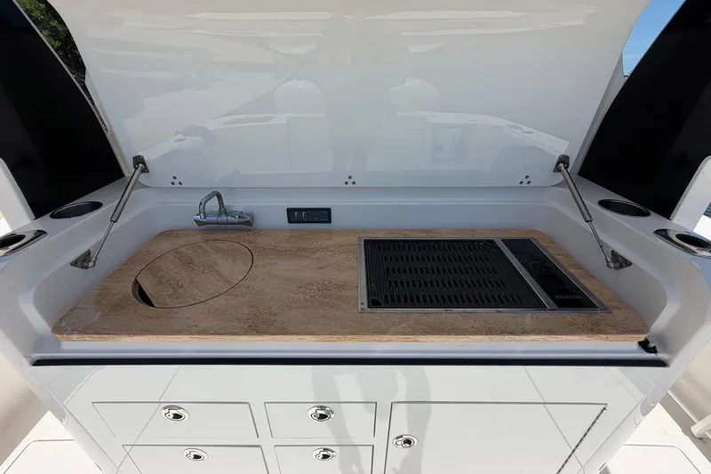 Slide: The Image of 2016 Edgewater 368CC boat kitchenette with sink and grill, featuring storage drawers. - 23