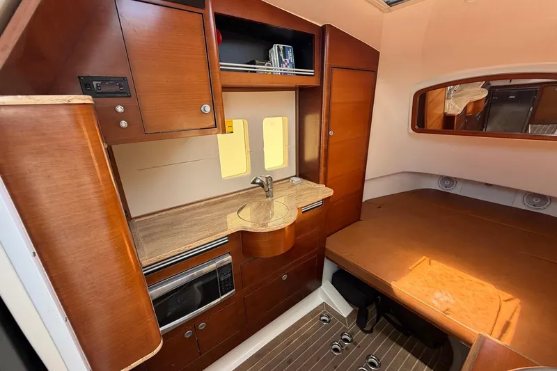 Slide: The Image of 2016 Edgewater 368CC cabin interior with wood cabinetry, compact kitchen, and cozy sleeping area. - 43