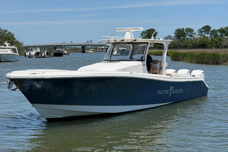 Slide: The Image of 2016 Edgewater 368CC boat on water near a bridge and greenery. - 3