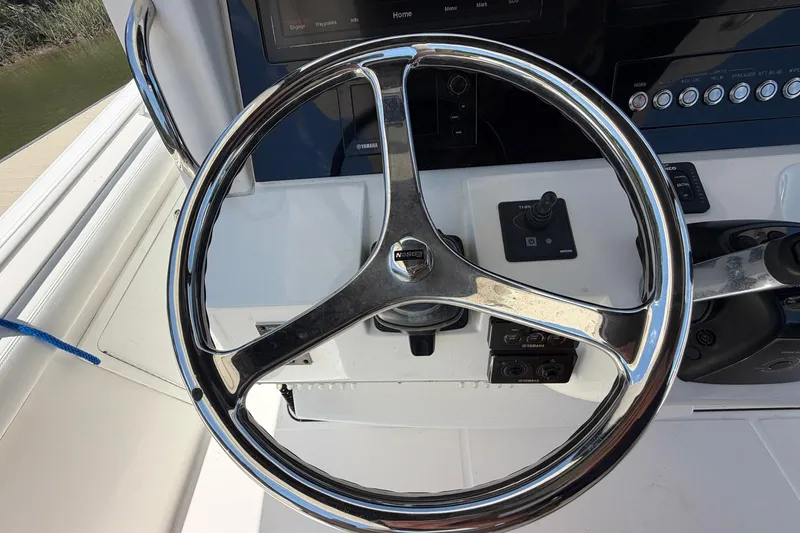 Slide: The Image of Steering wheel of a 2016 Edgewater 368CC boat, featuring a polished metal finish. - 62