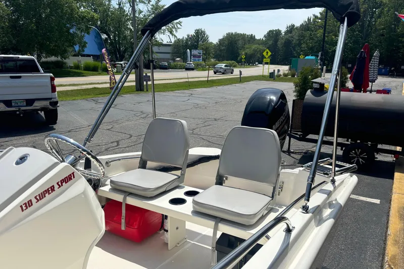 Slide: The Image of 2019 Boston Whaler 130 Super Sport boat with seating and canopy in a parking lot. - 7